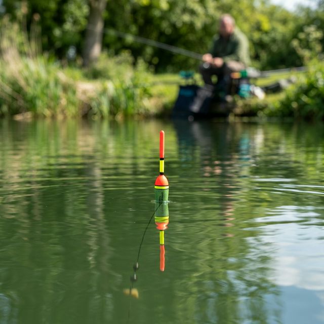 Pêcheur au coup avec flotteur sur une rivière calme en France